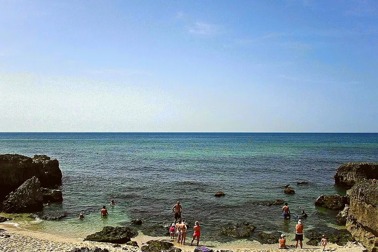 Mar transparente e formações rochosas da Praia do Evaristo no Algarve.