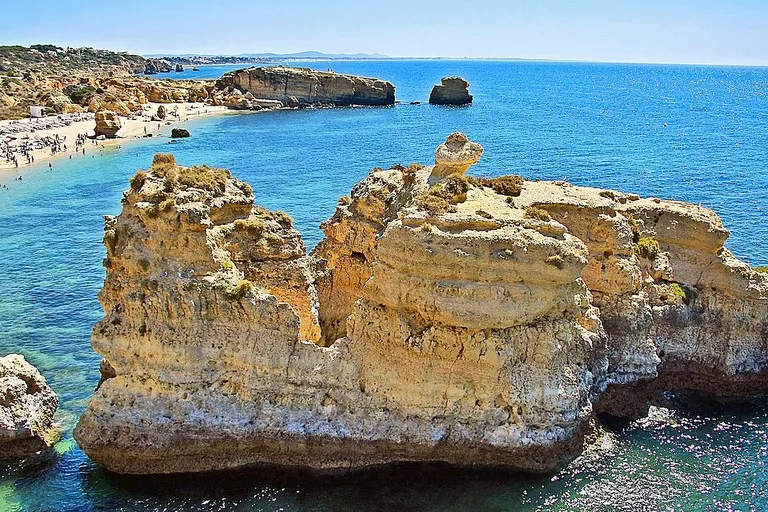 Vista panorâmica da Praia de São Rafael em Albufeira, com falésias douradas a contrastar com o mar azul-turquesa.